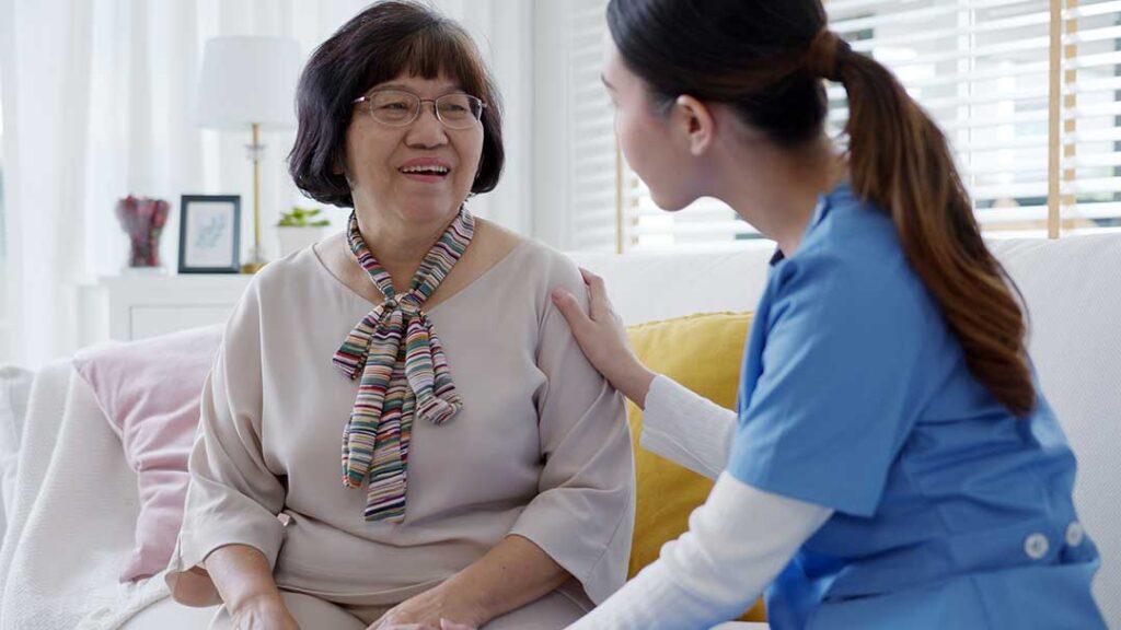 Family member and assisted living resident reviewing health care documents with a staff member at a table.